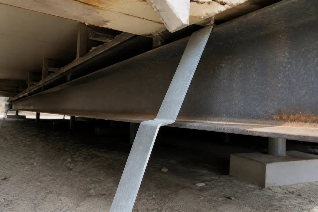 A tie-down strap passing over the edge of a chassis beam
