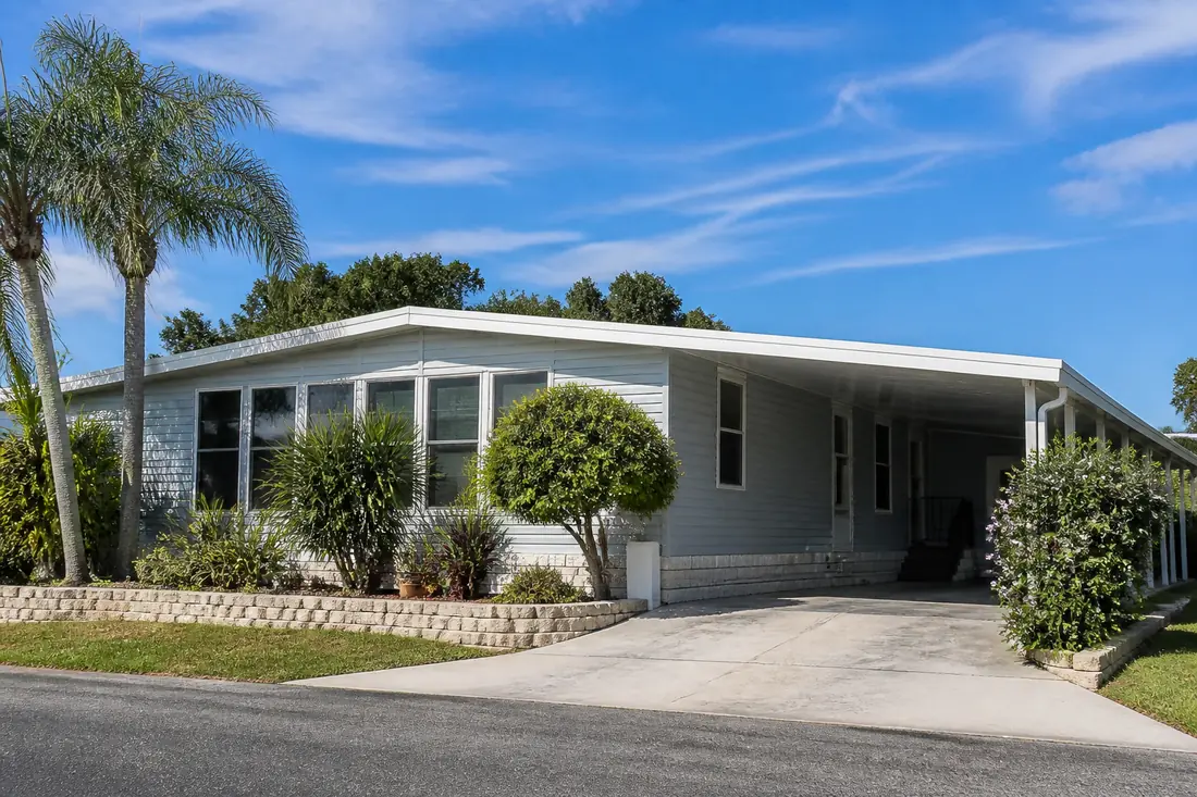 A manufactured home with a newly finished white roof-over under a wide Central Florida sky